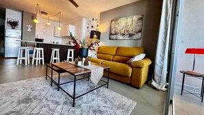 Ein modernes Wohnzimmer mit einer Couch, einem Couchtisch und einem Essbereich mit Hockern.