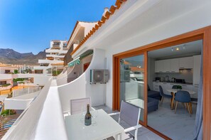 A balcony with a table and chairs, a bottle of wine, and a view of a mountain.