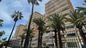 Un hotel de varios pisos con balcones, rodeado de palmeras.