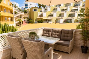 A patio with wicker furniture, a glass table, and a potted plant. - Orlando Pool View and cozy terrace (Costa Adeje)