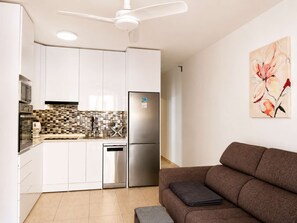 A modern kitchen with white cabinets, a stainless steel refrigerator, and a tiled backsplash. - Orlando Pool View and cozy terrace (Costa Adeje)