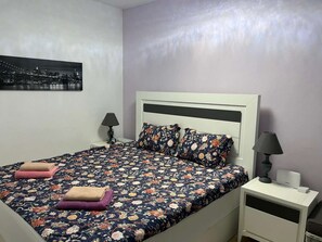 A bed with a floral bedspread, a white headboard, and two nightstands with lamps.