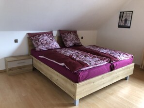 A single bed with a wooden frame and a purple bedspread.