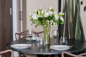 A dining table with a vase of white flowers, empty wine glasses, and plates set for a meal.