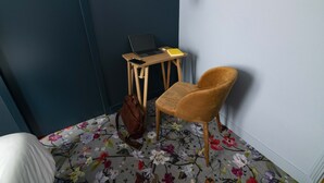A room with a bed, a chair, a desk with a laptop and a phone, and a handbag on the floor. - Naâd Hotel (Sarlat-la-Canéda)