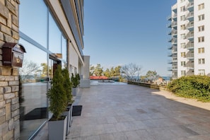 A modern building with large windows, a stone facade, and a paved courtyard.