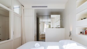 Una camera d'albergo moderna con un letto grande, un armadio, uno specchio e una libreria.