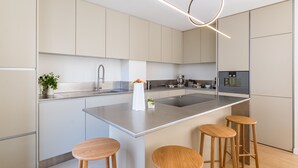 Una cucina moderna con isola centrale, elettrodomestici in acciaio inossidabile e sgabelli in legno.