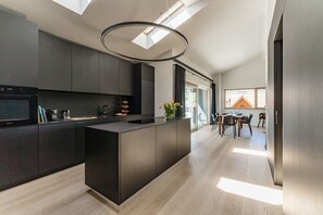 A modern kitchen with a central island, dark cabinetry, and a skylight. - City Fischer Design Apartment (Schladming)