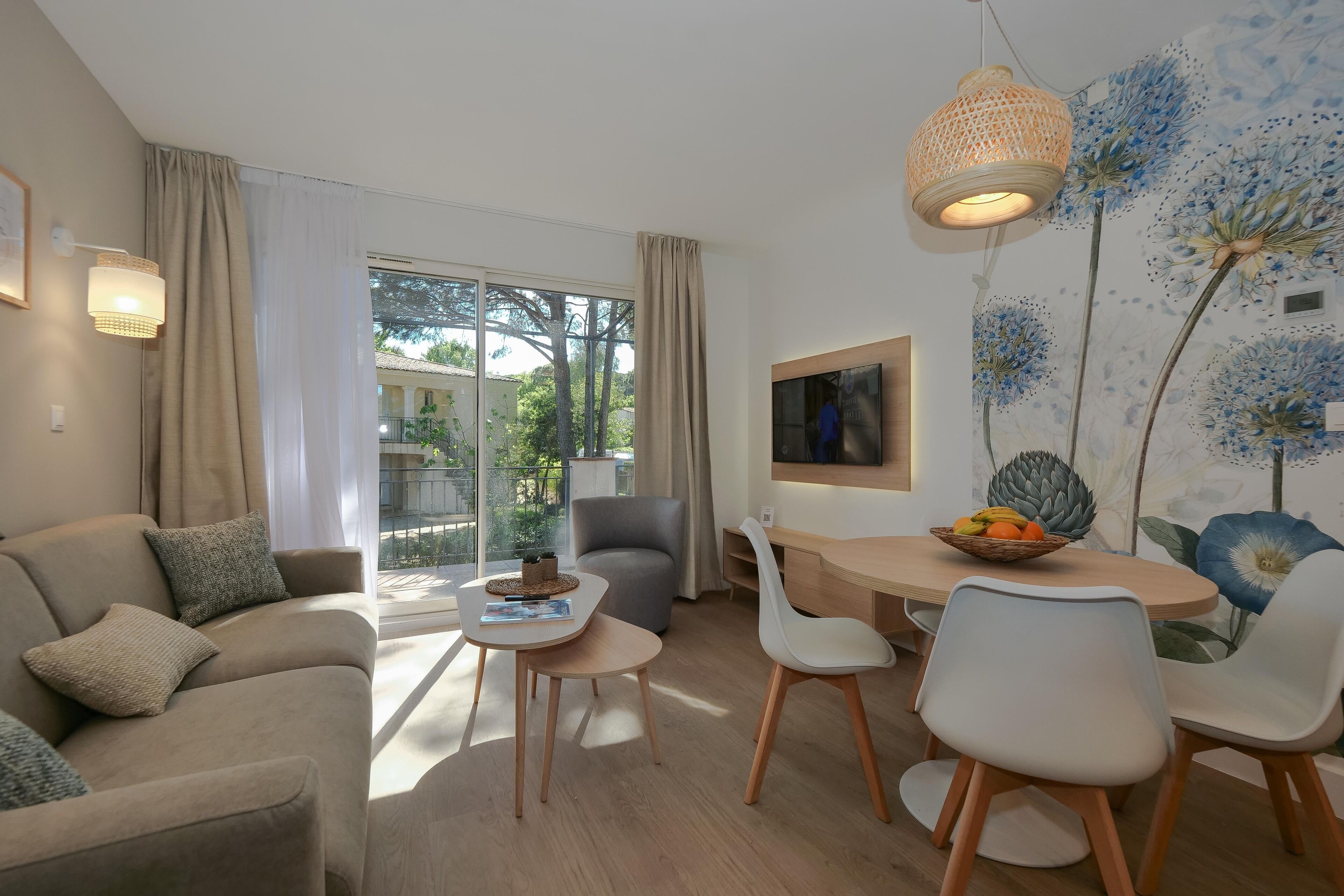 Een moderne woonkamer met een bank, eettafel, stoelen en een groot raam met gordijnen.