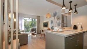 Una cocina moderna con una isla central, luces colgantes y una zona de comedor con un sofá y sillas.