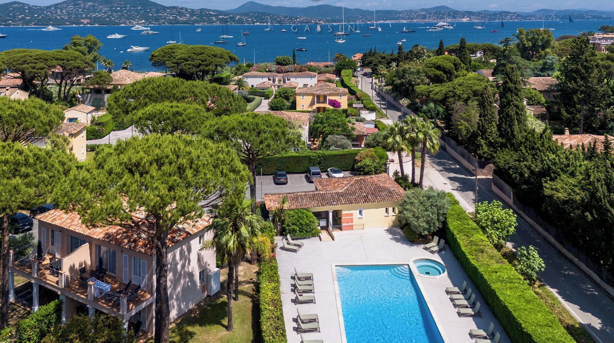 Propiedad residencial con piscina, vista al mar y montañas al fondo.