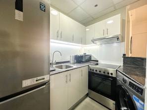 Functional kitchen with stainless steel appliances, oven, and ample countertop space for food preparation.