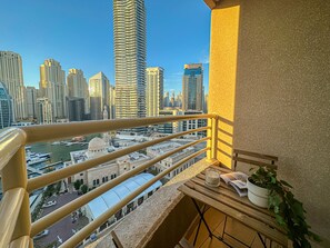 Enjoy the city view from this balcony with a table, candle holder, and potted plant.