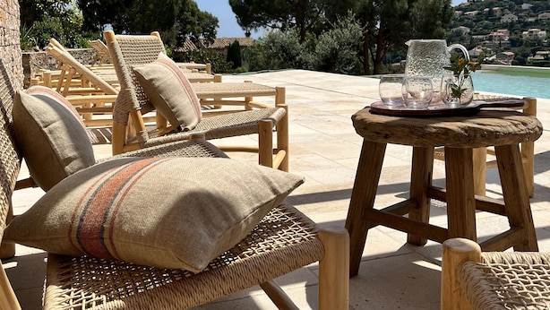Outdoor wicker furniture with cushions, a small wooden table with a pitcher and glasses, and a view of a coastal landscape with trees and buildings. - La maison de la Genette 5* Luxe -Sea view-Pool-1,5 km from the sea-12 persons (Cavalaire-sur-Mer)