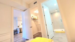 A hotel room with a bed, a bathroom, and a kitchen area visible through an open door. - 2-bedroom apartment just 12 minutes to Port of Palm Beach (West Palm Beach)