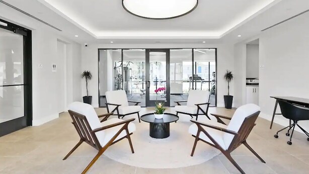 A modern hotel lobby with a round coffee table, white chairs, a large circular light fixture, and a view of the gym through glass doors. - 2-bedroom apartment just 12 minutes to Port of Palm Beach (West Palm Beach)