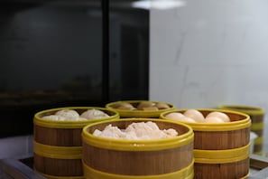 Vários vapores de bambu com comida no interior, dispostos numa bandeja.