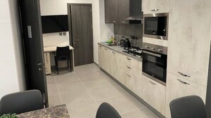 Une cuisine compacte avec un coin repas, comprenant un four à micro-ondes, une cuisinière et des placards.