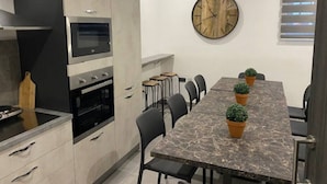 Une cuisine moderne dotée d’un four encastré, d’un four à micro-ondes et d’un coin repas avec une table et des chaises en marbre.