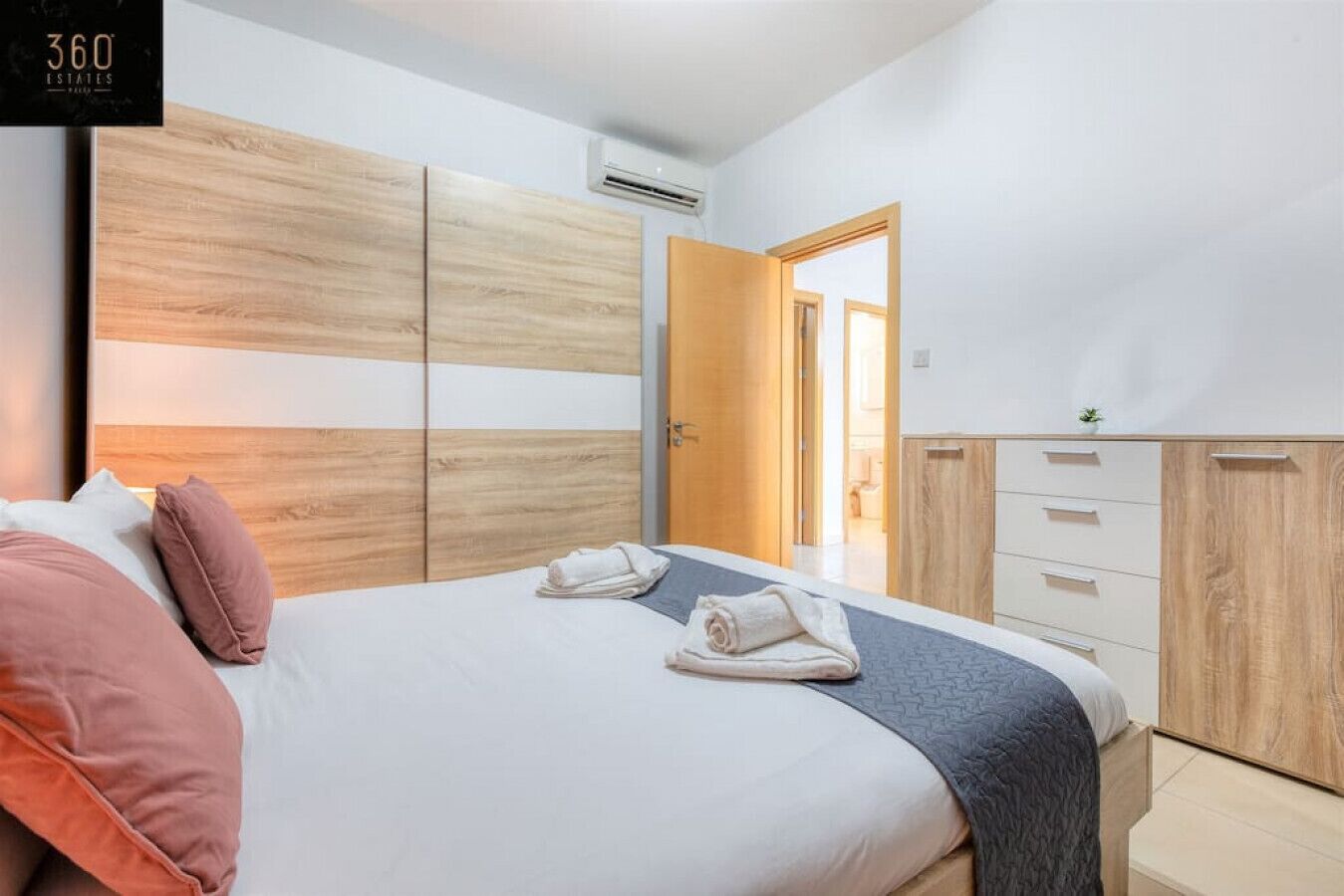 Ein modernes Schlafzimmer mit einem Bett, einem Holz-Kopfteil und einem Kleiderschrank.