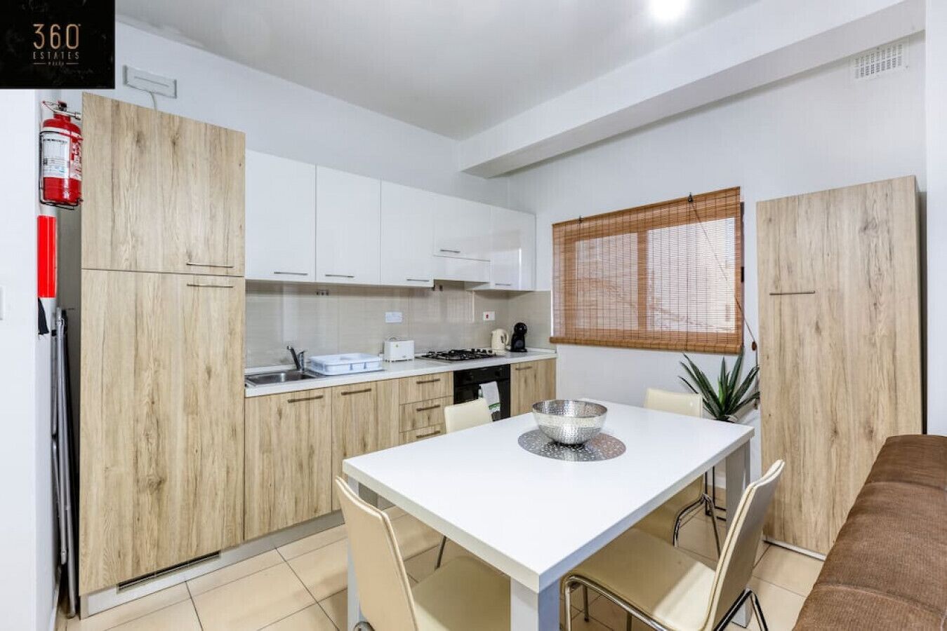 A modern kitchen with white cabinets, a dining table, and a fire extinguisher.