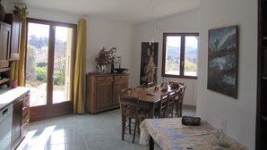 Ein Essbereich mit Tisch, Stühlen, einem Schrank und einem Gemälde an der Wand.