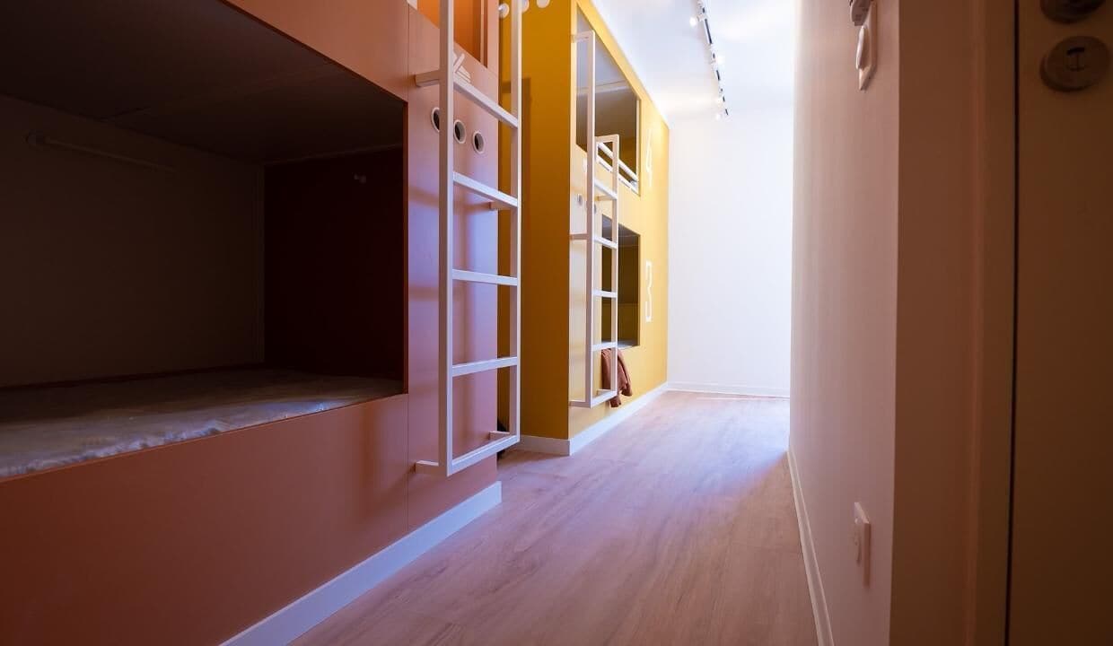 A hallway with a wooden floor, a white door, and a yellow wall.