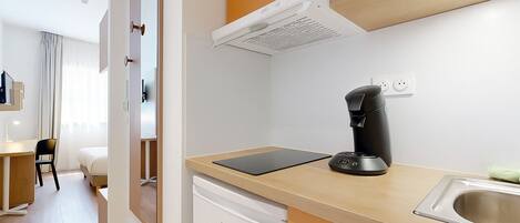 Una cocina moderna con cafetera, lavamanos y encimera.