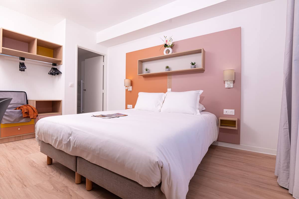 Une chambre moderne avec un grand lit, un plancher en bois, des étagères intégrées et une table de chevet.