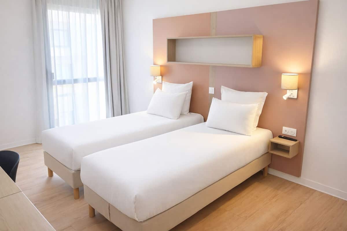 Une chambre avec un lit double, deux tables de chevet, une étagère murale et une fenêtre avec des rideaux.