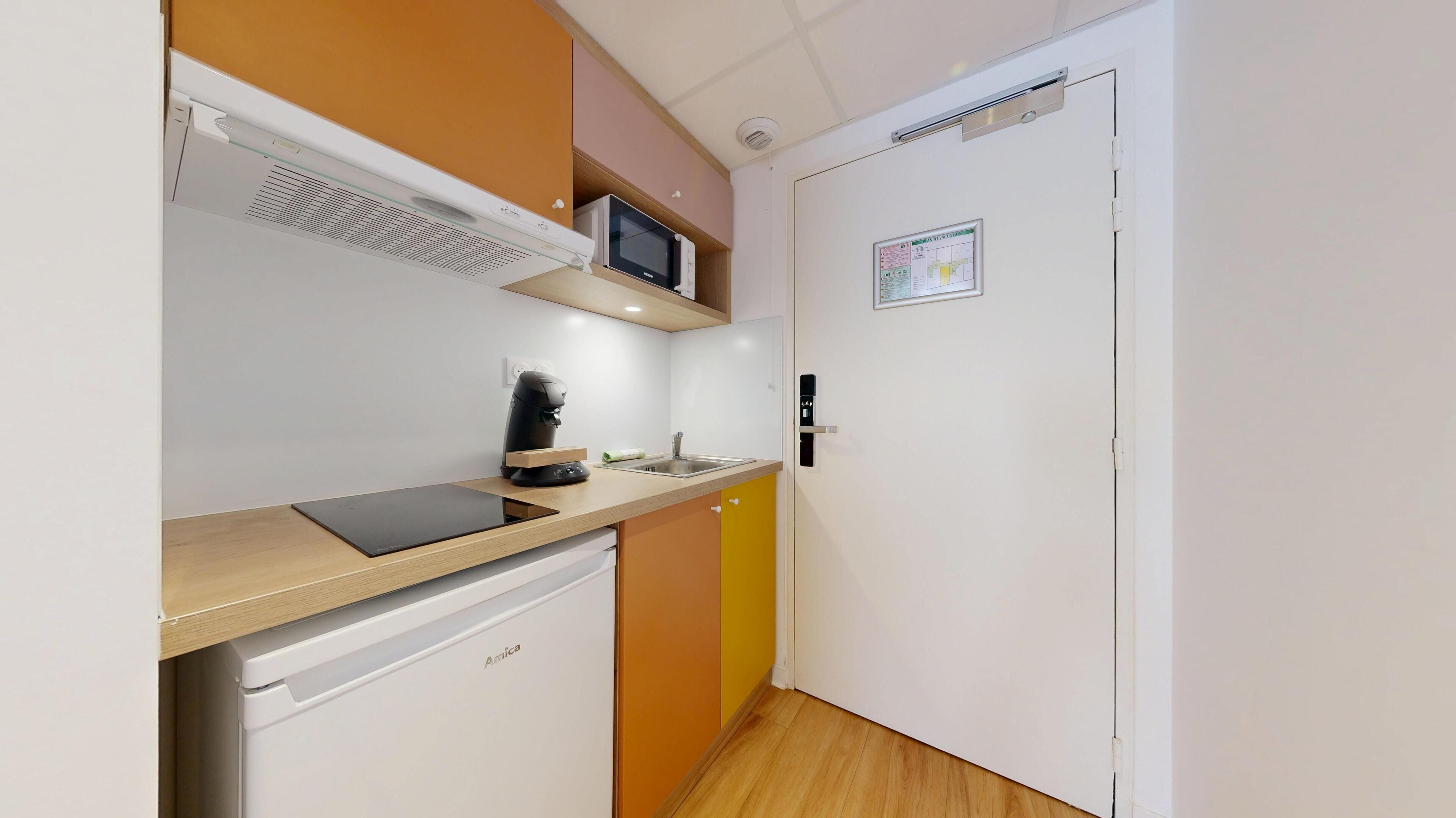 Una kitchenette compacta con microondas, cafetera y pileta.