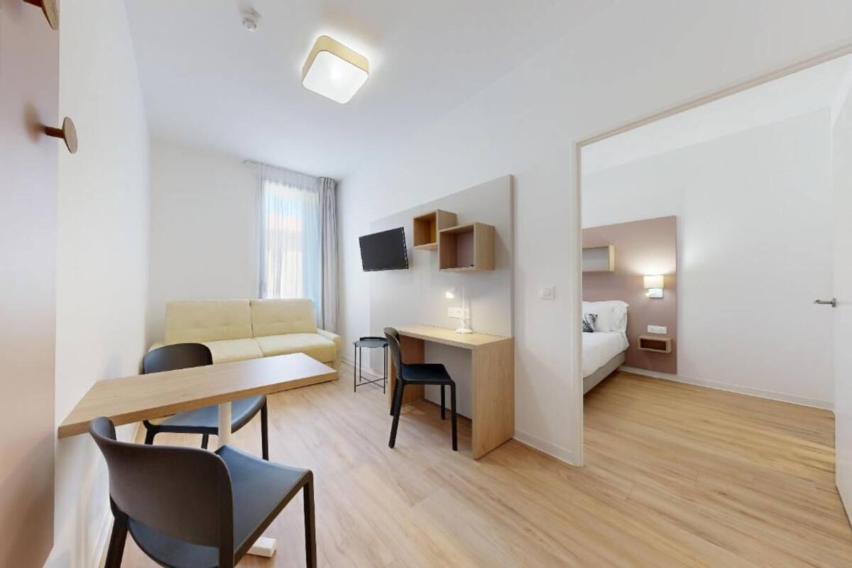 Une chambre d’hôtel moderne équipée d’un canapé, d’un bureau, d’une chaise, d’une télévision et d’un lit.
