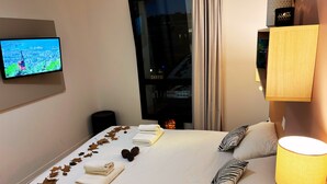 A hotel room with a bed, a TV on the wall, a fireplace, and a window with curtains. - Apparthôtel Privilodges Toulon Centre Gare (Toulon)