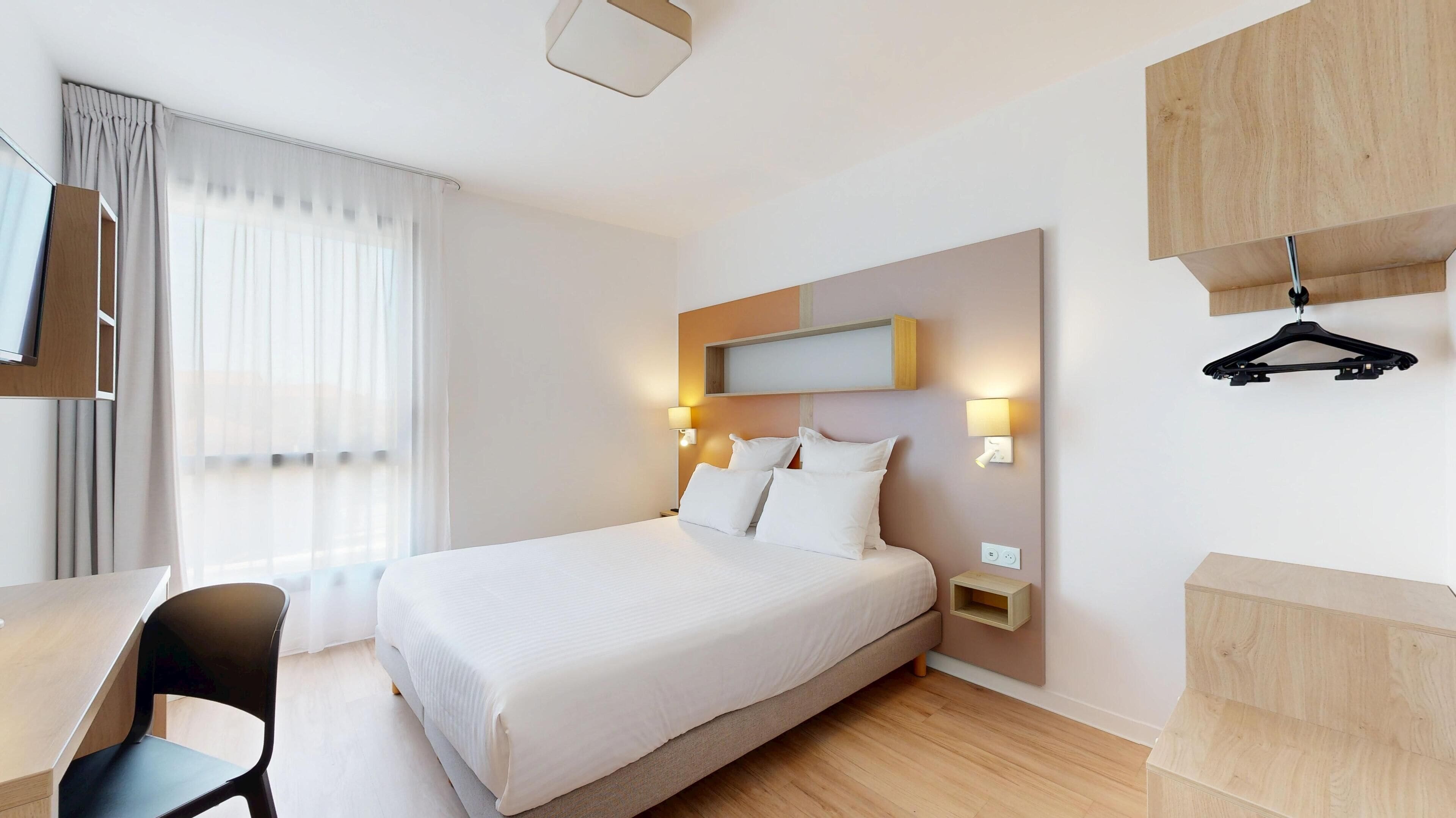 Una habitación de hotel moderna con una cama grande, un escritorio y una silla.