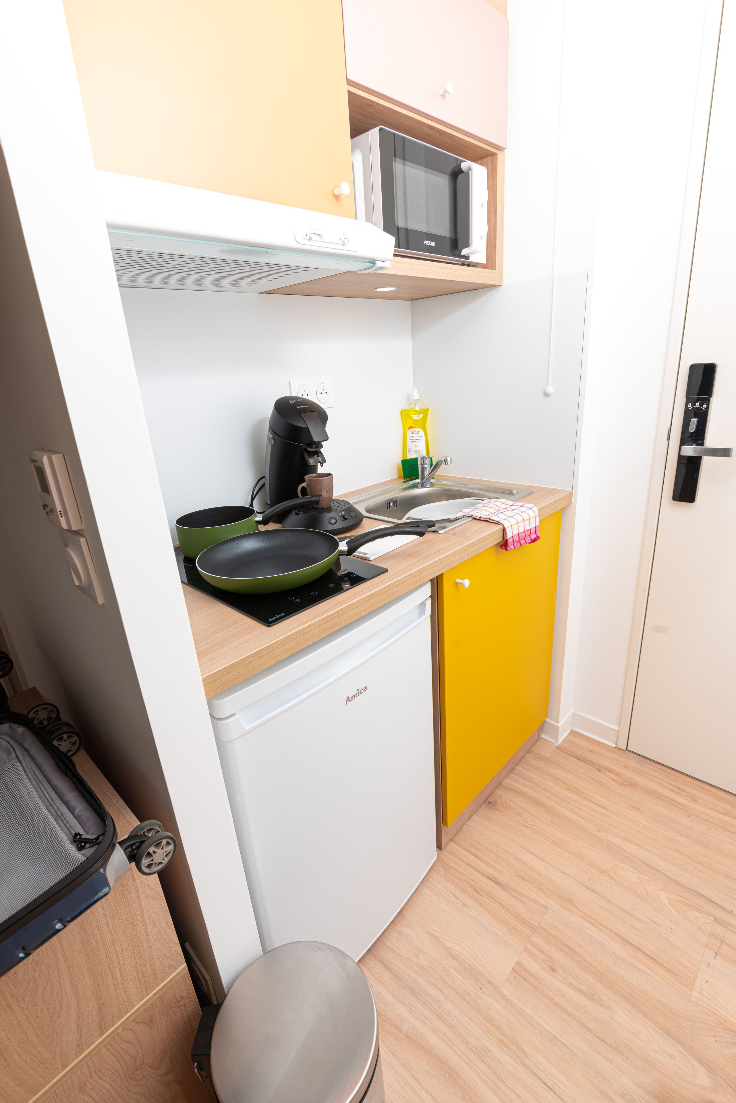 A compact kitchen with a microwave, coffee maker, and a small sink.
