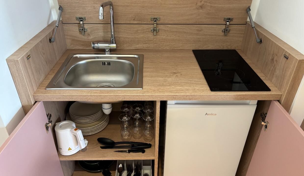 A compact kitchen with a sink, stove, and storage cabinets.