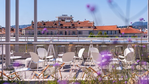 A terrace with white chairs and tables, overlooking a building with red-tiled roofs. - Apparthôtel Privilodges Toulon Centre Gare (Toulon)