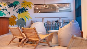 A modern interior with wicker chairs, a white table, and a large abstract mural on the wall. - Apparthôtel Privilodges Toulon Centre Gare (Toulon)