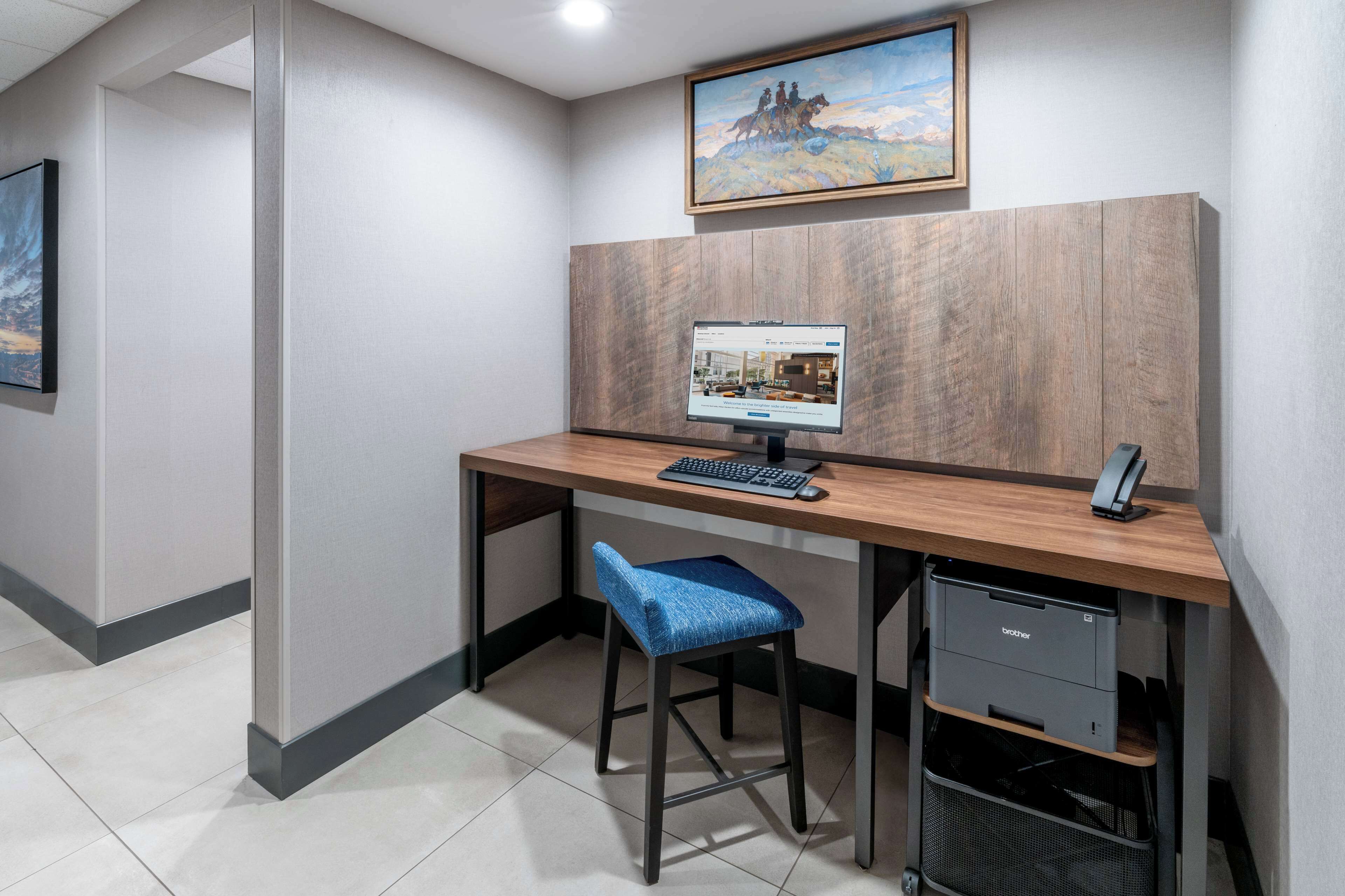 A modern office cubicle with a wooden desk, a computer, a blue chair, and a filing cabinet.