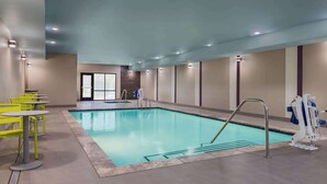 An indoor swimming pool with a clear water surface, surrounded by a tiled floor and walls. There are yellow chairs and a pool ladder. - Home2 Suites By Hilton El Centro (El Centro)