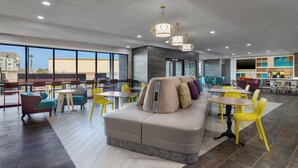 A spacious indoor area with a large sofa, multiple tables and chairs, and a modern ceiling design. - Home2 Suites By Hilton El Centro (El Centro)