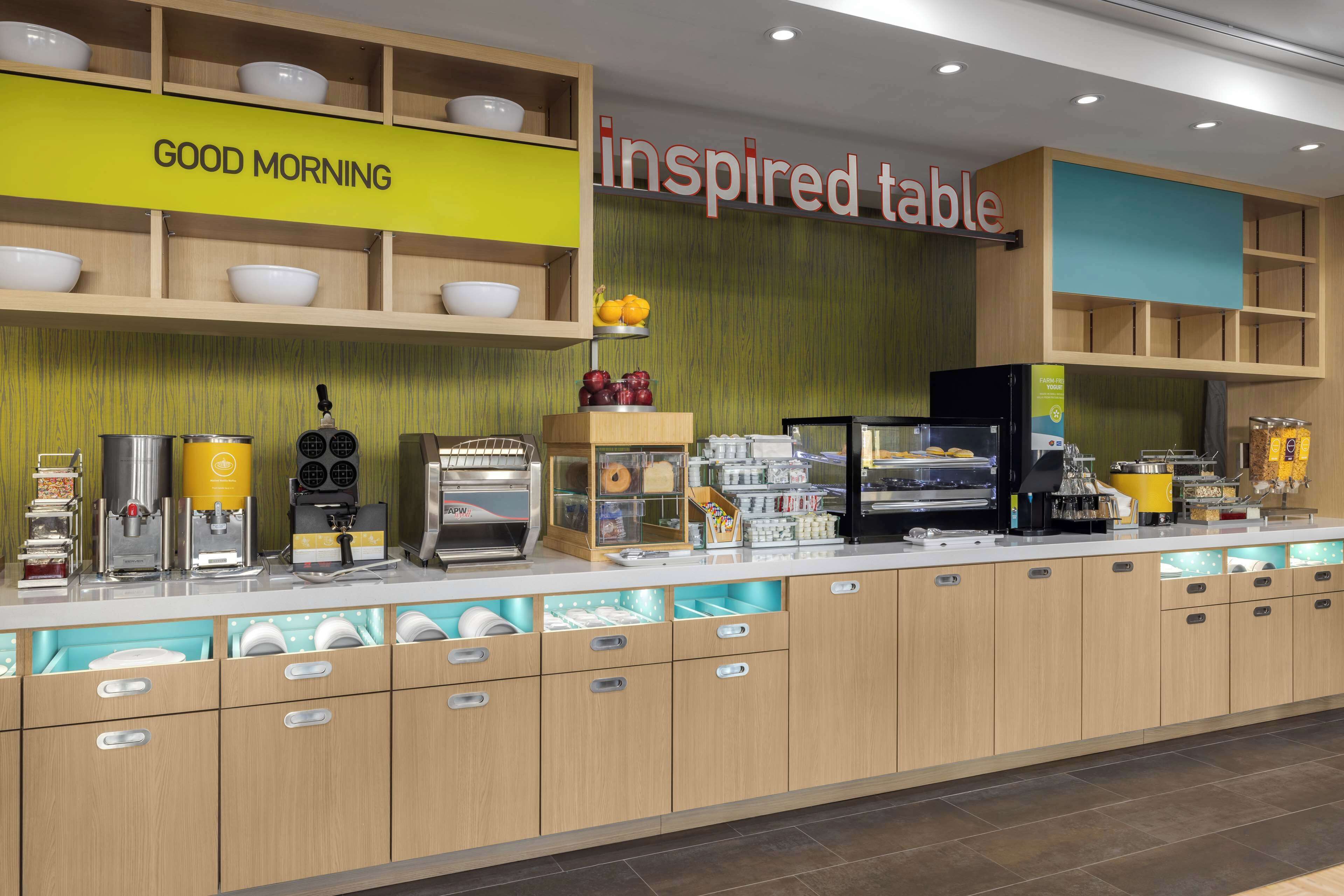 A breakfast bar with a 'Good Morning' sign, a 'Inspired Table' sign, and various breakfast items and appliances.