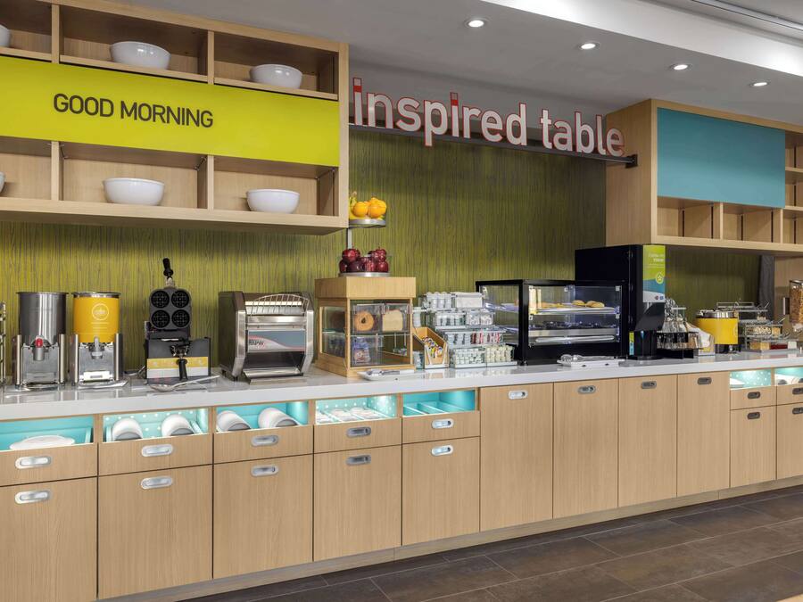 A breakfast bar with a 'Good Morning' sign, a 'Inspired Table' sign, and various breakfast items and appliances.