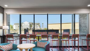 A modern hotel lobby with a large window view, seating area with chairs and sofas, and a central round table. - Home2 Suites By Hilton El Centro (El Centro)