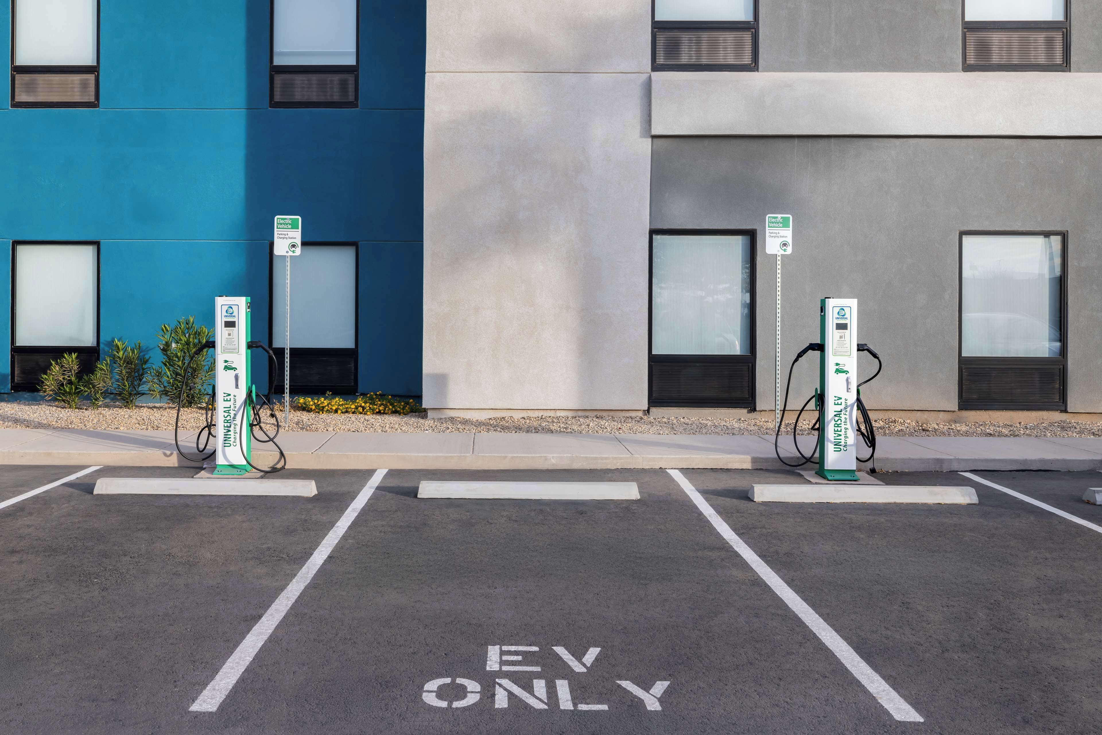 An EV charging station area with a building in the background.