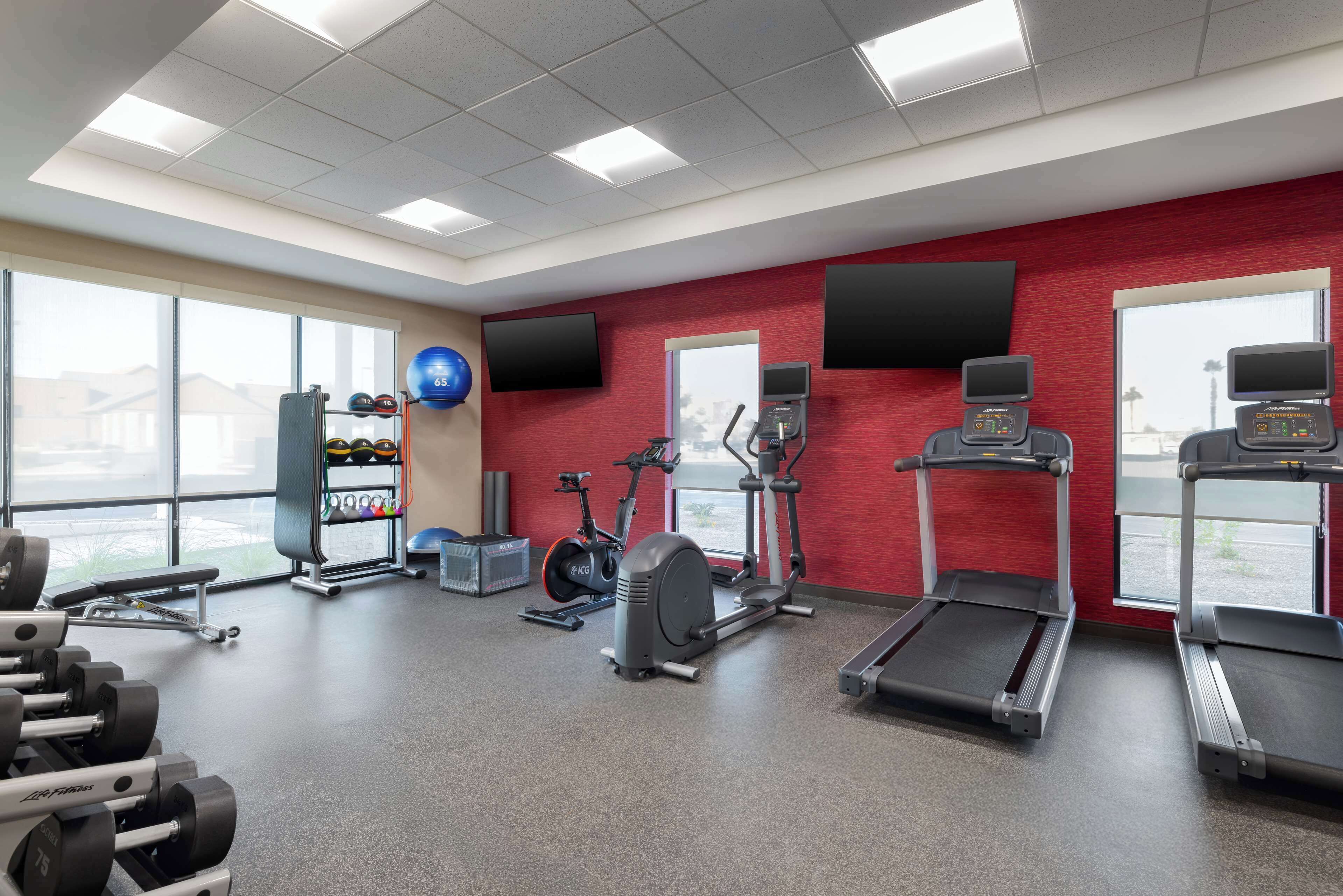 Un gimnasio con cintas de correr, elípticas y equipos de levantamiento de pesas.