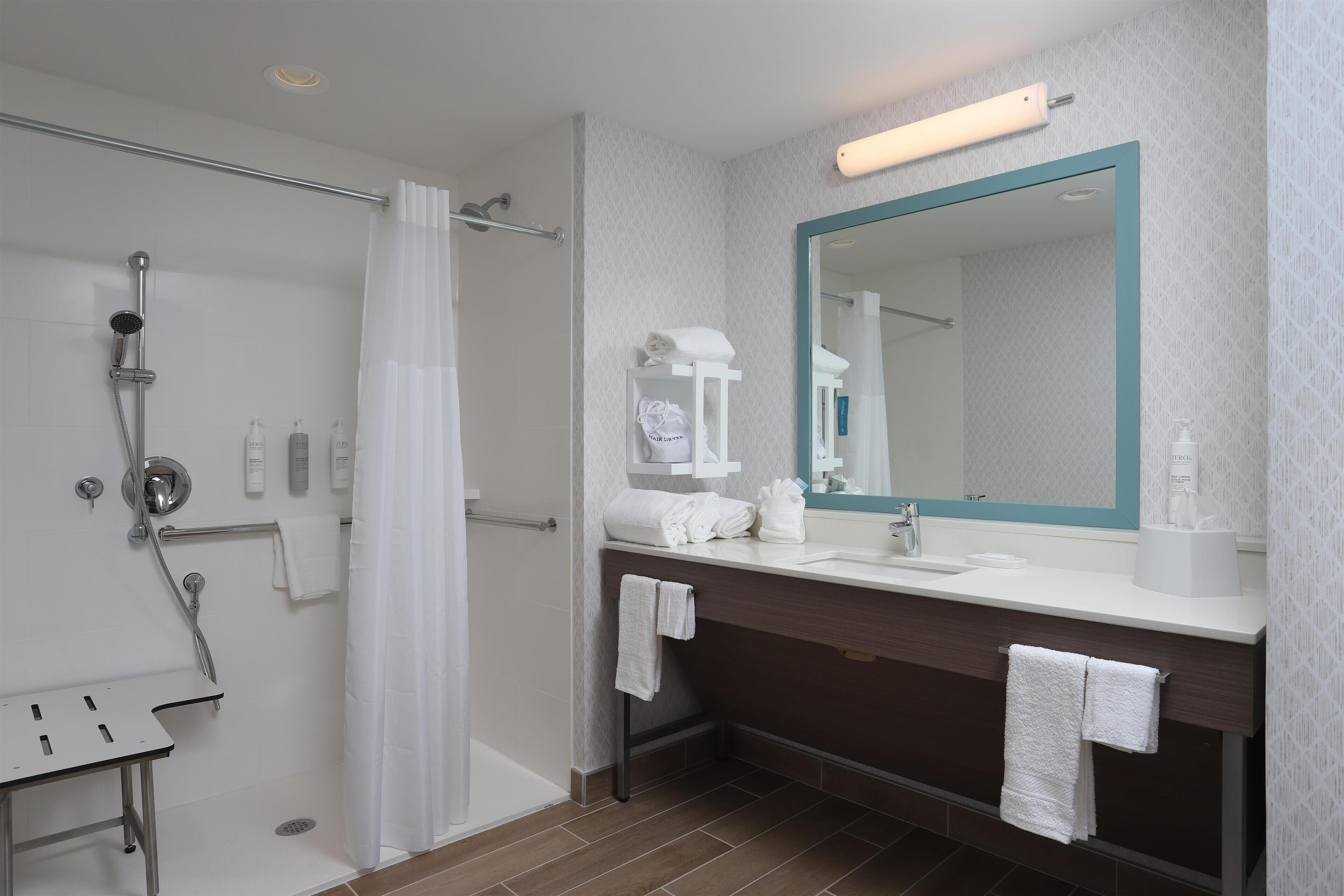 A modern bathroom with a shower, a sink, a mirror, and a towel rack.