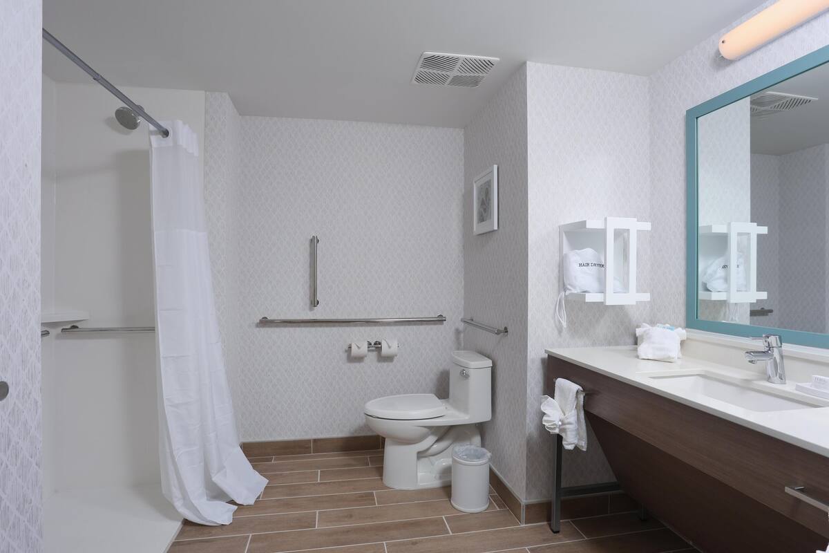 A modern bathroom with a shower, toilet, and sink.