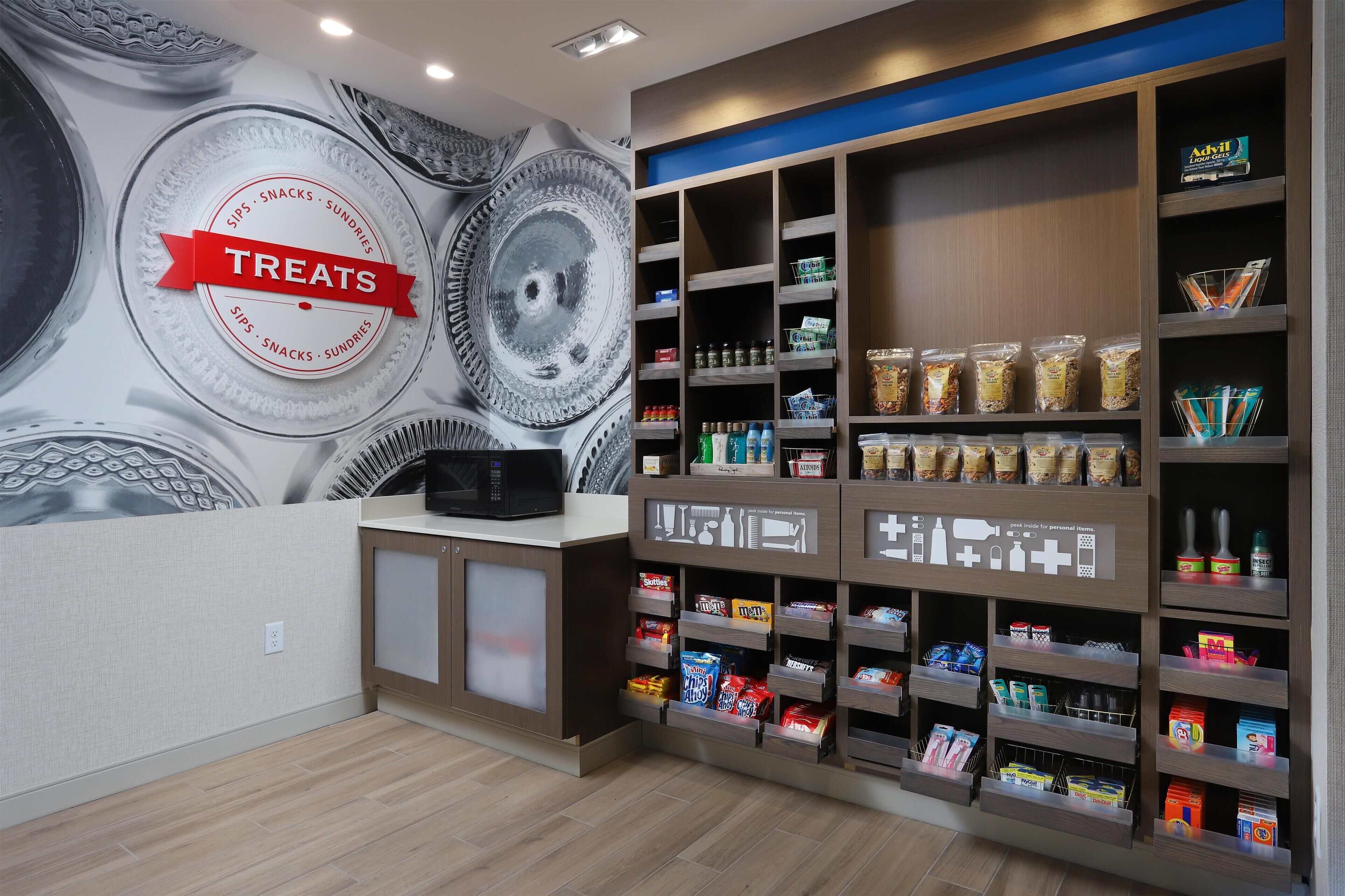Un bar proposant des collations, avec une enseigne indiquant « Friandises », des étagères remplies de snacks, de boissons et de condiments.